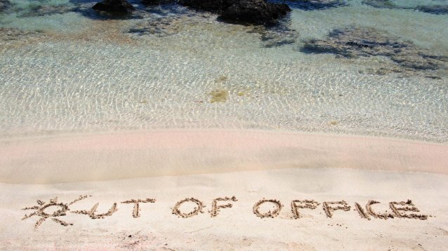 OUT OF OFFICE written on sand on a beautiful beach, blue waves i
